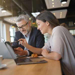 Jonge sales vrouw toont producten op laptop tijdens informele bijeenkomst